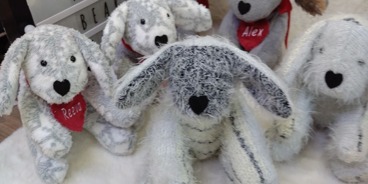 Five plush dog toys with heart-shaped noses and red bandanas.