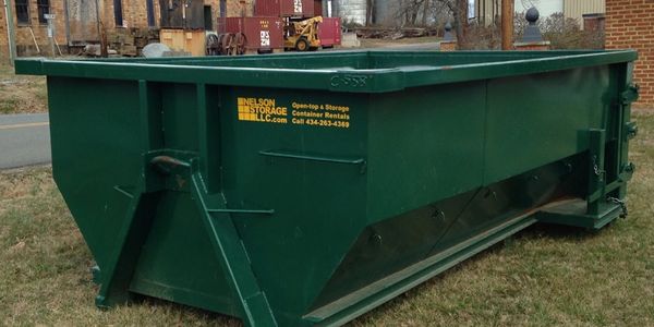 A green Nelson Storage open top dumpster sits at a job site
