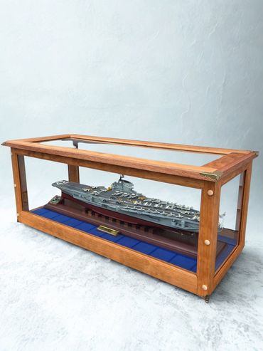 Glass-top wooden display table with a ship model inside.