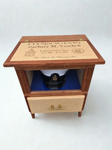 Retirement display cabinet with an engraved sloped lid and a Navy cap inside.
