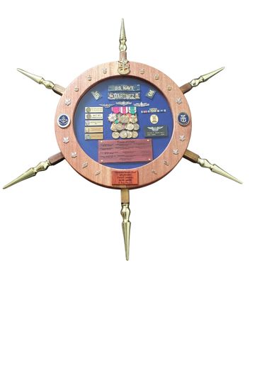 Ship-wheel display with military medals, ribbons, and an American flag.