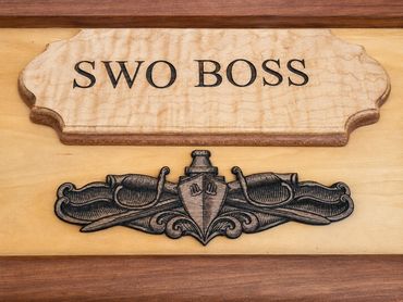 Close-up of the SWO BOSS wood plaque and engraved surface warfare insignia.