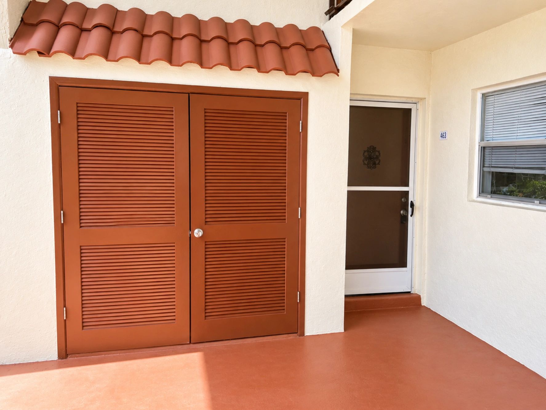 Covered entry patio of a ground-floor South Florida condo with louvered doors.
