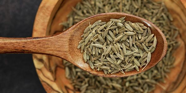 Wooden spoon with cumin seeds.