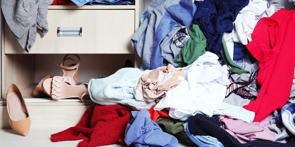 A drawer and a big pile of clothing and shoe clutter.