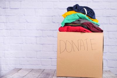 A cardboard donation box filled with clothes.