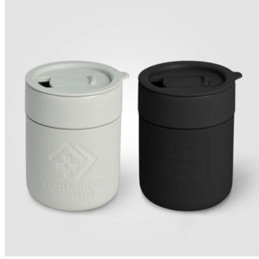 Two cylindrical containers, one white and one black, with lids and embossed logos.