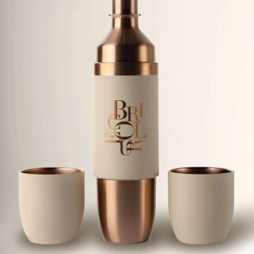 Elegant copper and cream cocktail shaker set with two matching cups.