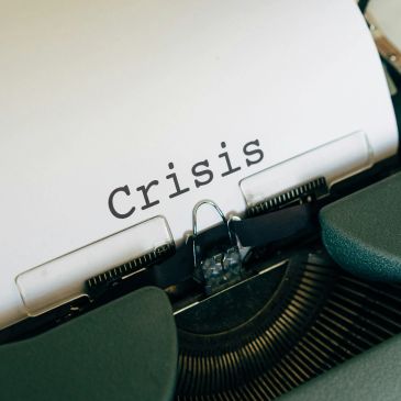 The word 'Crisis' typed on a sheet of paper in a typewriter.
