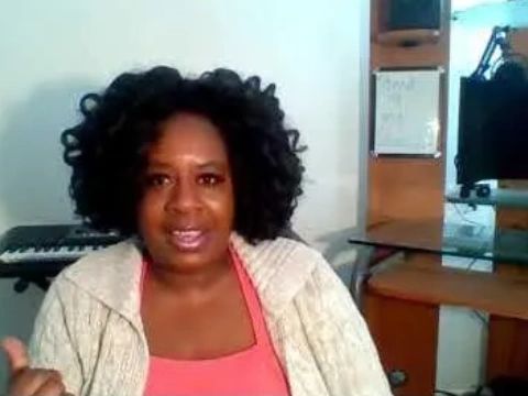 Black woman sitting at studio wearing pink shirt