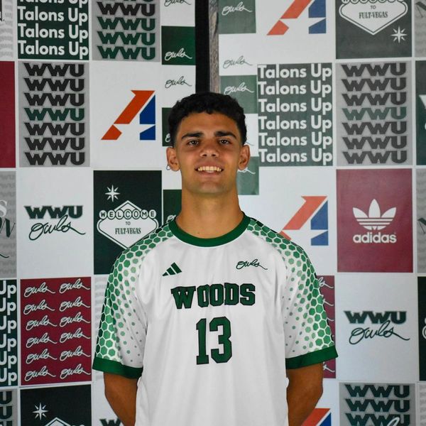 Young male athlete in a Woods sports jersey standing against a branded backdrop.