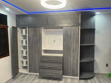 Modern gray wardrobe with multiple compartments and drawers in a room.