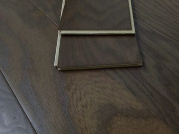 Close-up of dark wood laminate flooring samples on a wooden floor.