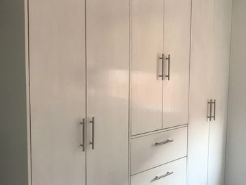 White wardrobe with multiple doors and drawers in a room corner.