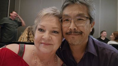 A smiling couple posing closely for a selfie indoors.