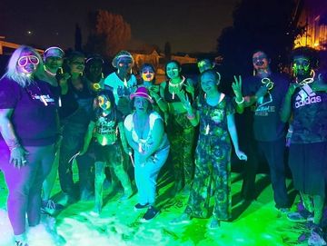 Group of people enjoying a night event with colorful lights.