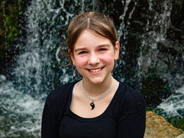Smiling girl with waterfall background.