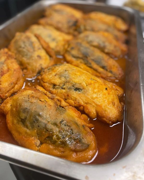 Fried stuffed peppers in a sauce.