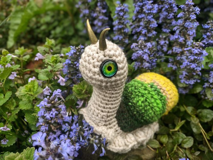 Crocheted snail in spring flowers