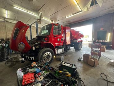 A red truck is in the garage with tools.