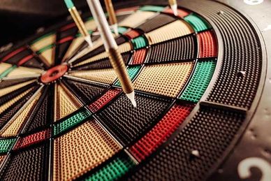 Three darts hitting a colorful dartboard closely grouped.
