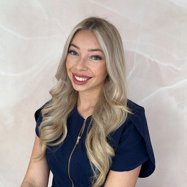 Smiling woman with long blonde hair in a navy blue top.