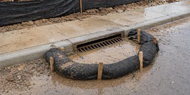 A sandbag barrier around a street drain at a construction site.