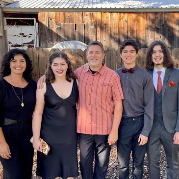 Five people standing shoulder to shoulder in front of an outdoor barn.