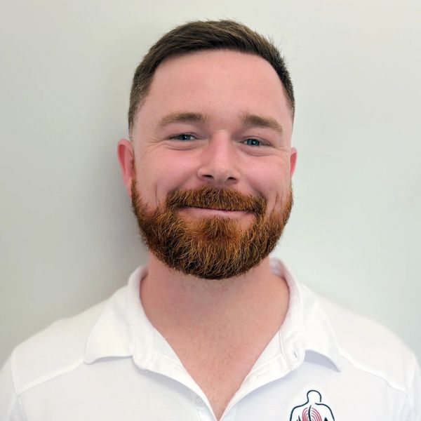 Smiling man with a red beard wearing a white polo shirt.