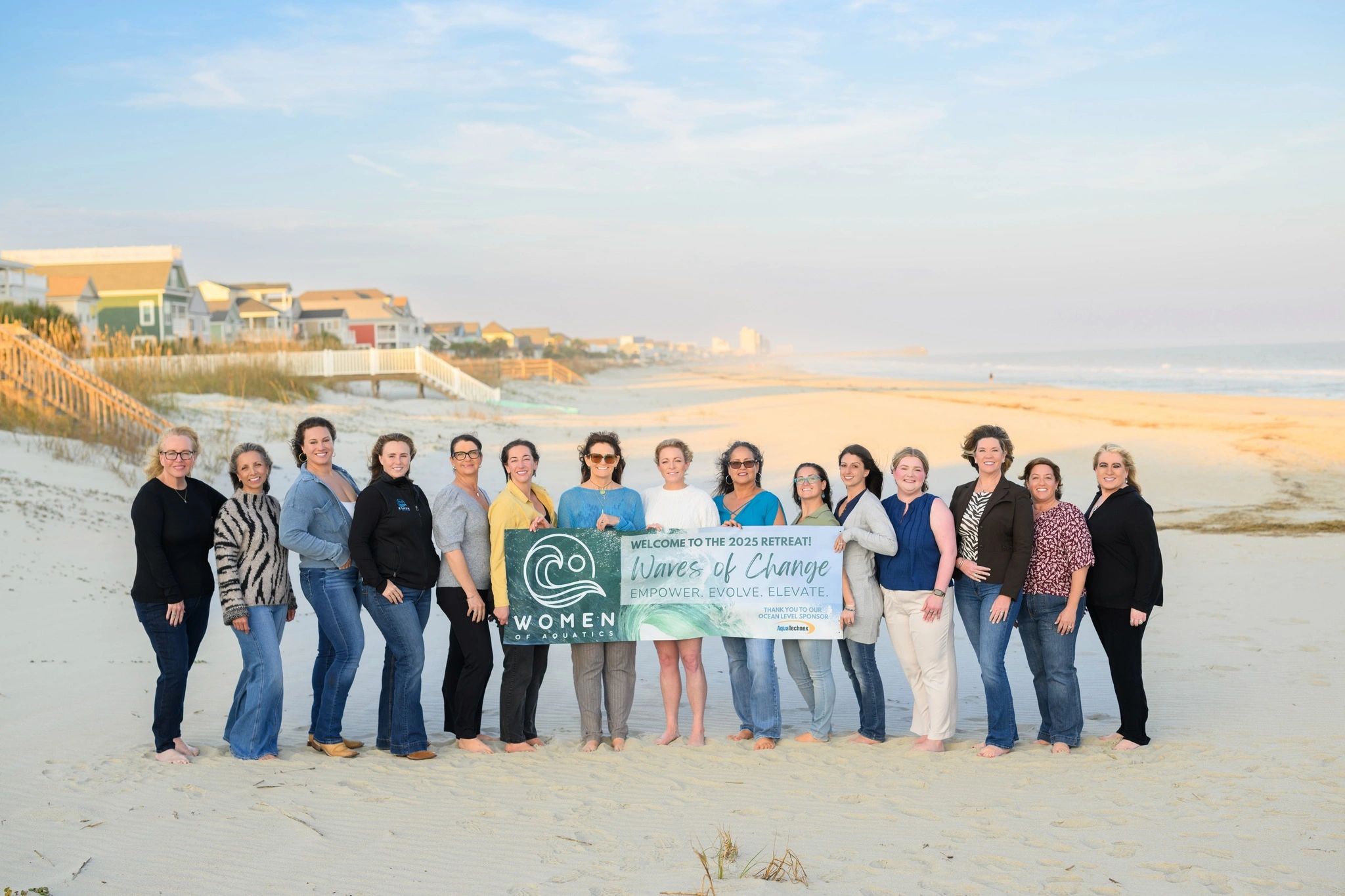 Group of women on a beach holding a retreat banner.