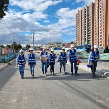 Group of engineers wearing safety helmets and vests walking on a construction site.