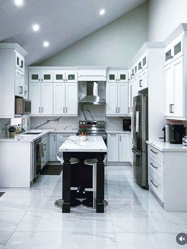 a newly renovated modern white kitchen with a lack island and white countertops with matching floors