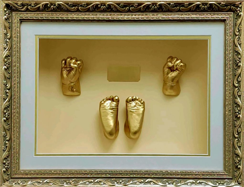 Framed golden casts of baby hands and feet as a keepsake.