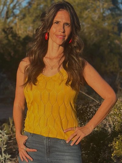 Woman in yellow top with long hair outdoors.