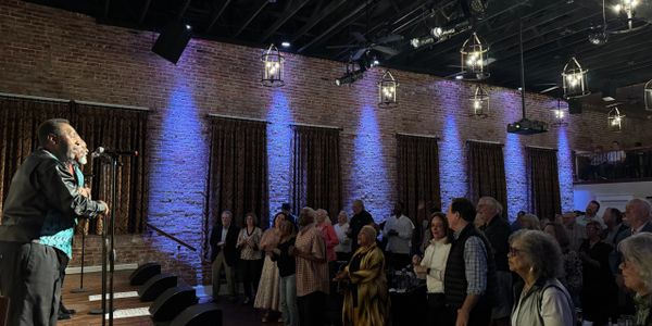A lively indoor event with a singer and an engaged audience in a rustic venue.