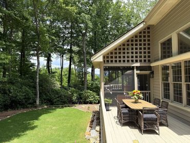 Garden and side exterior view of Woodsong showing the lawn, wooded setting, deck, and private mountain-retreat atmosphere near Lake Toxaway.