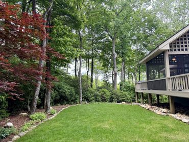 Garden and side exterior view of Woodsong showing the lawn, wooded setting, deck, and private mountain-retreat atmosphere near Lake Toxaway.