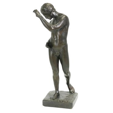 Bronze sculpture of a nude male figure in a contemplative pose.