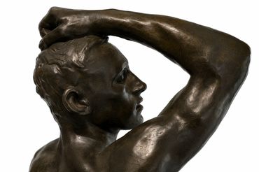 Bronze sculpture of a man with arm raised.