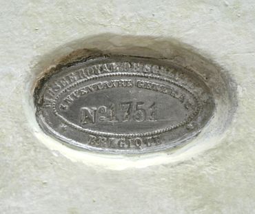 Metal plaque on a wall with the number 1751 and Belgian text.