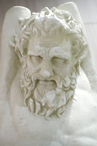 Close-up of a marble sculpture of a bearded man with a solemn expression.