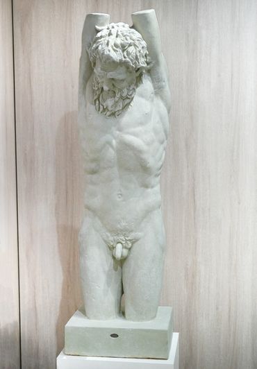 Marble statue of a bearded man with raised arms, missing forearms.