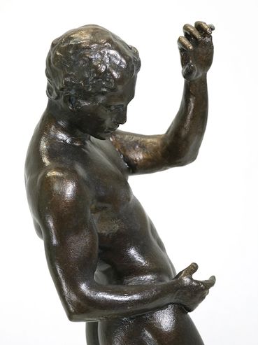 Bronze sculpture of a young man in a dynamic pose.