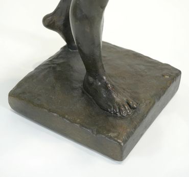 Close-up of the modeled foot and textured rectangular base of Athlete, Male Nude, showing the dark b