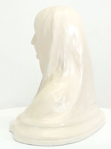 Side view of a white bust sculpture draped in cloth.
