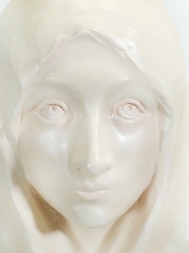 Close-up of a smooth, white marble bust of a serene female figure.