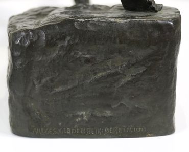 Close-up of a bronze sculpture base with engraved text.