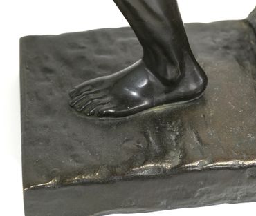 Close-up of a black sculpture's foot on a textured base.