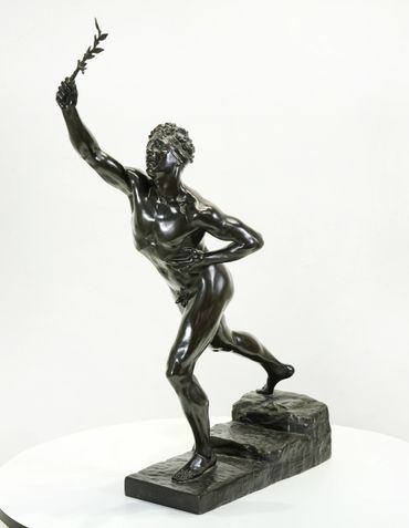 Bronze statue of a blindfolded male figure holding a branch, posed dynamically.