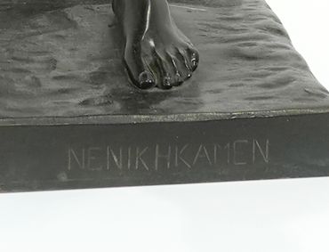 Close-up of a statue's foot with the inscription 'NENIKH KAMEN' on the base.